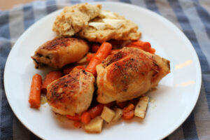 Chicken Thighs, carrots and parsnips on plate with buttered biscuit