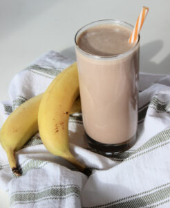 chocolate peanut butter banana smoothie in a glass next to bananas