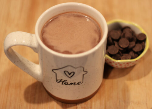 Mug of hot chocolate next to dish of chocolate chips