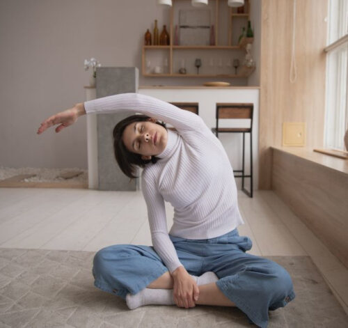 Woman sitting on floor and exercising by stretching