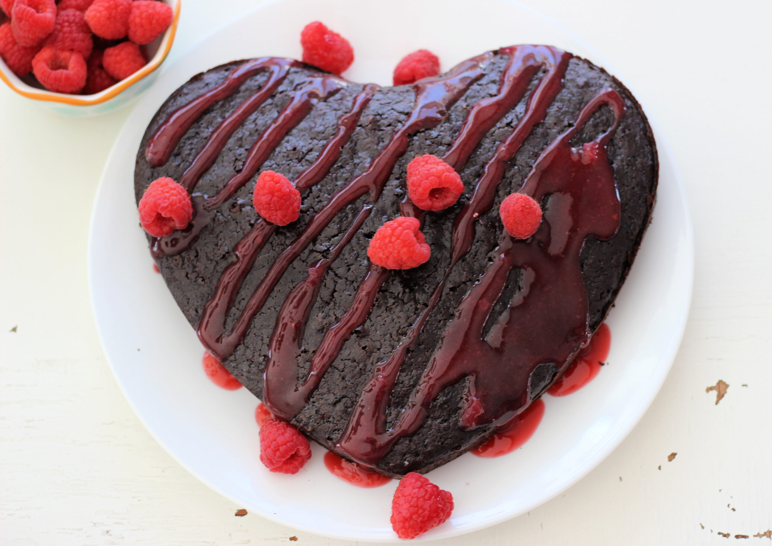 Heart shaped cake with raspberry sauce and fresh raspberries