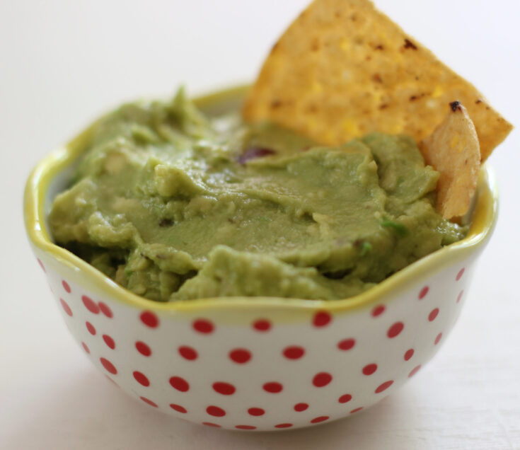 Guacamole with tortilla chip in red polka dot bowl